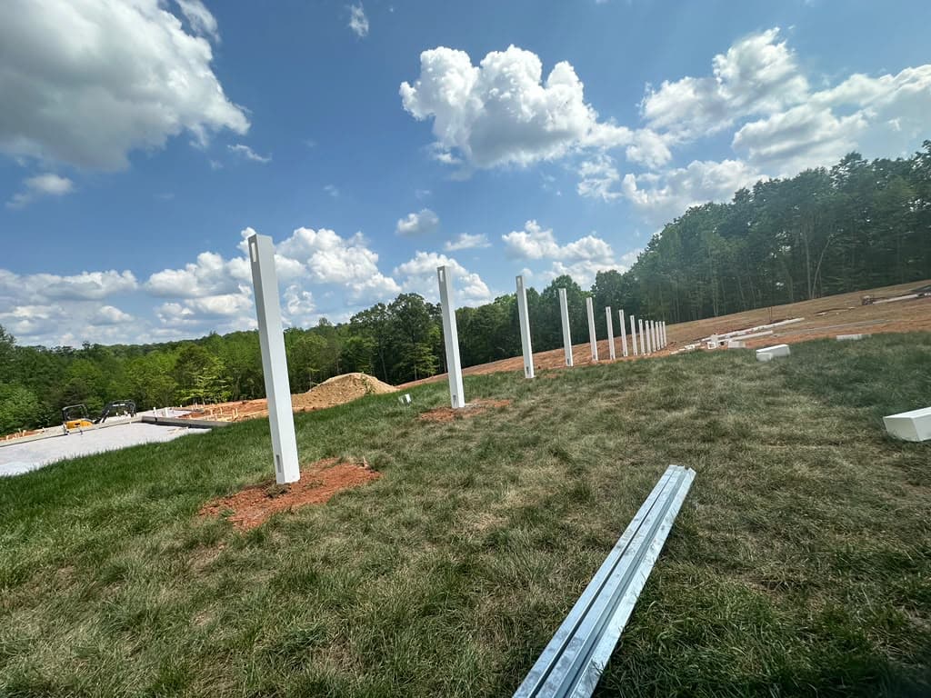 Fence posts set in a line across an open field, ready for panels